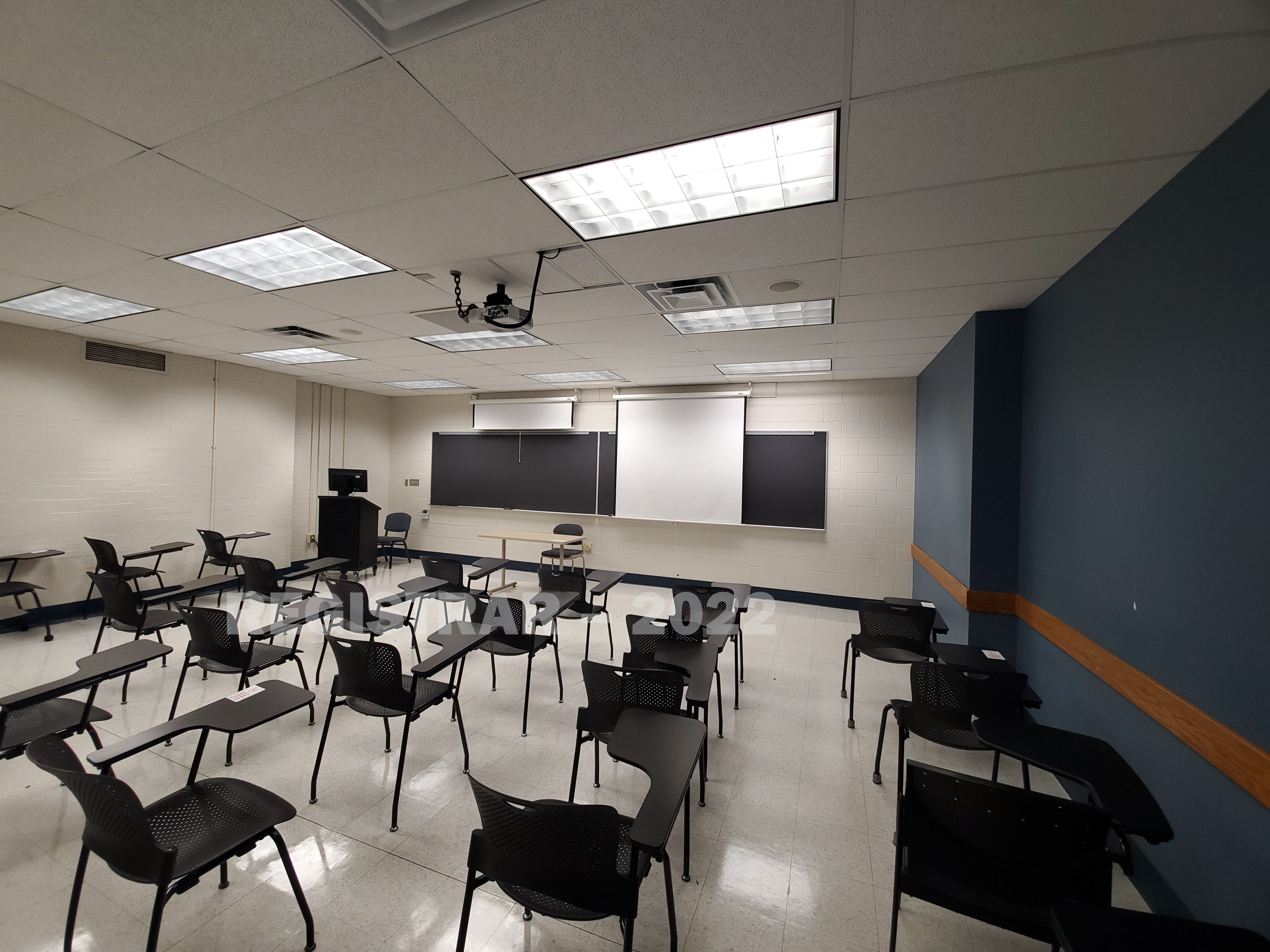 Journalism Building room 143 ultra wide angle view from the back of the room with projector screen down