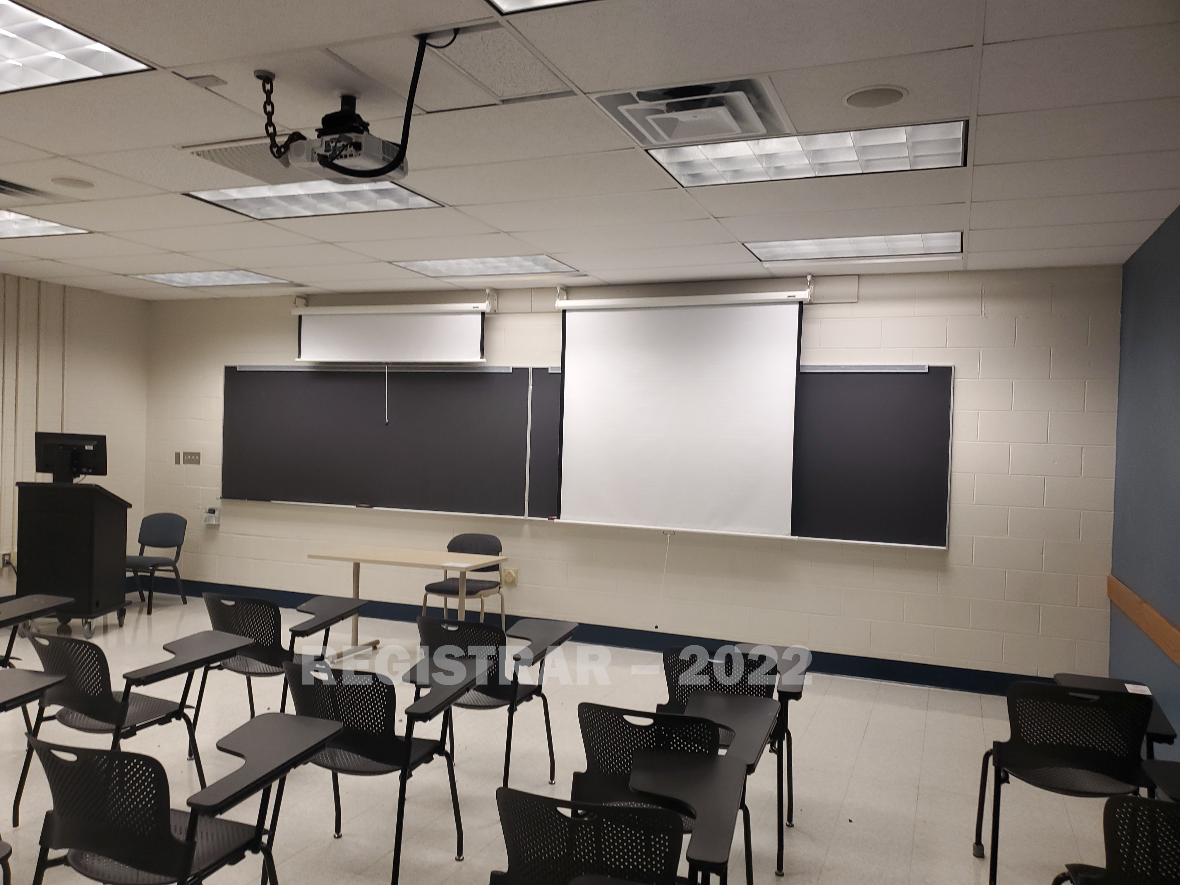 Journalism Building room 143 view from the back of the room with projector screen down